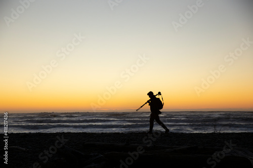 A photographer walking along the beach during sunset in Washington State