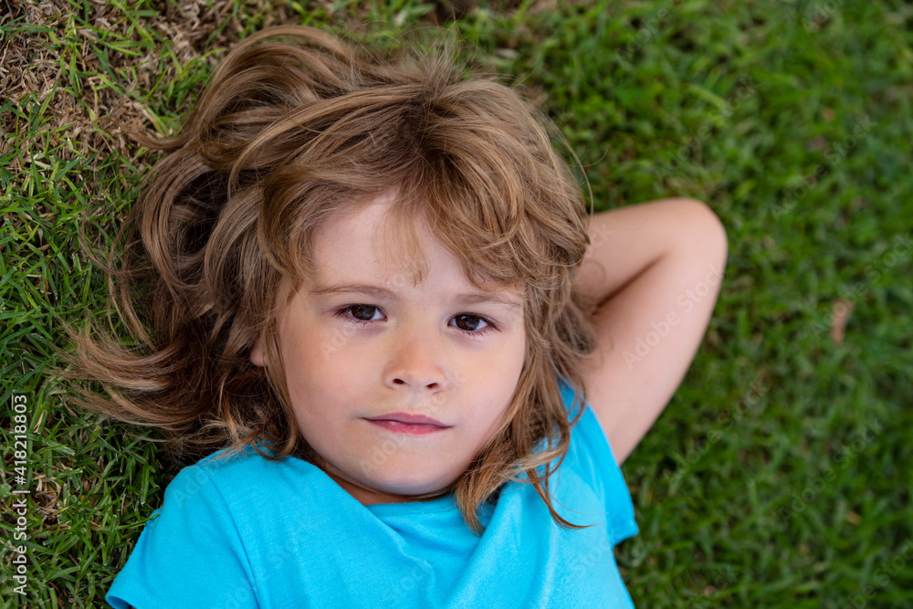 Cute boy lying in the grass. Handsome child enjoying on field or lawn and dreaming. Cute boy lying in the grass. Handsome child enjoying on field or lawn and dreaming.