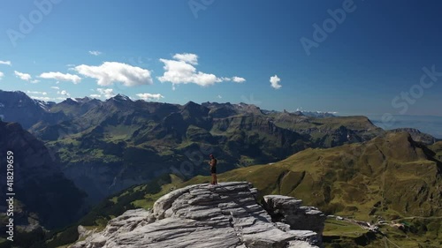 Drone shot of a man standing by himself all alone on top of Rotstock in Switzerland. Circling around him to show the epic and majestic landscape of mountains, valleys and green and lush nature around. photo