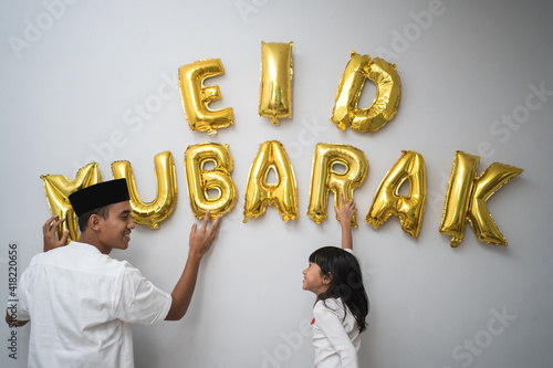Foto portrait father and daughter muslim decorating eid mubarak letter made of baloon