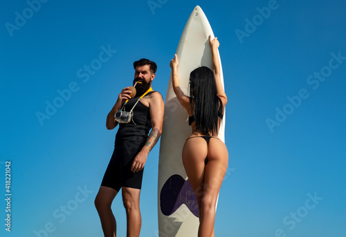 Summer couple vacation. Sexy woman in bikini hold serf board. Summertime concept. Sexy man in swimsuit. Surfboard. photo