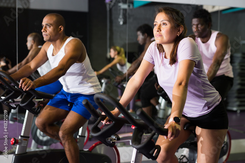 Group of adult people training on exercise bikes in gym