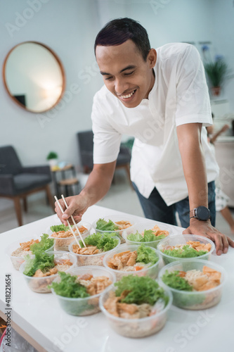happy young food business owner preparing his product at home