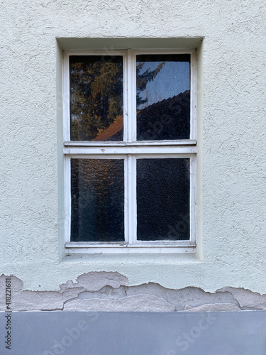 Sprossenfenster, vier Scheiben, Holz, in grauer Fassade und abbröckelten Putz