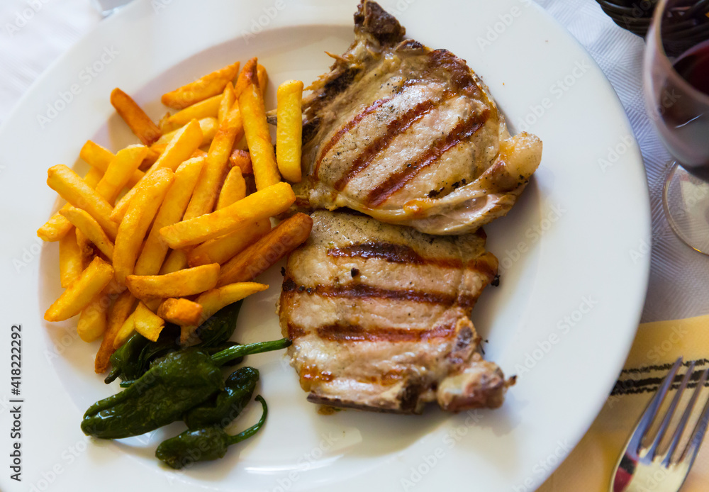 Grilled cutlet served with French fries and pickled pepper on plate
