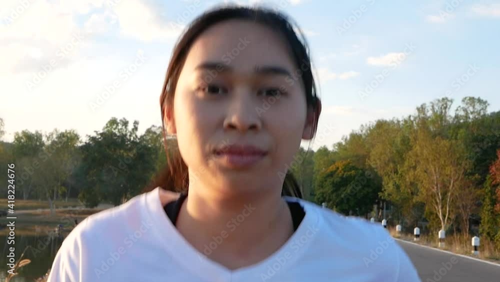 Close up shot of A healthy woman jogging run and workout on sunset lakeside road. Asian runner people exercise outdoor. Health care and Lifestyle Concept. Close up shot of A healthy woman jogging run and workout on sunset lakeside road. Asian runner people exercise outdoor. Health care and Lifestyle Concept.