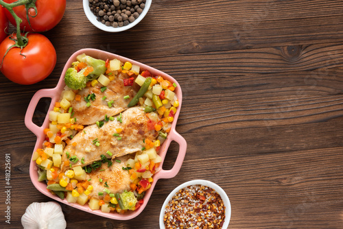 Baked chicken with vegetables on a wooden background. Top view. Copy space.