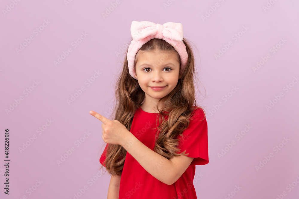 A little girl in a red T-shirt points her finger at the advertisement. A little girl in a red T-shirt points her finger at the advertisement.