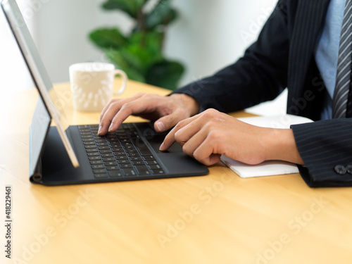 Businessman hands typing on tablet keyboard on the table in office room