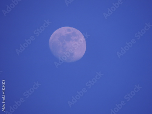 veiled moon with a dim light in a violet sky at sunset