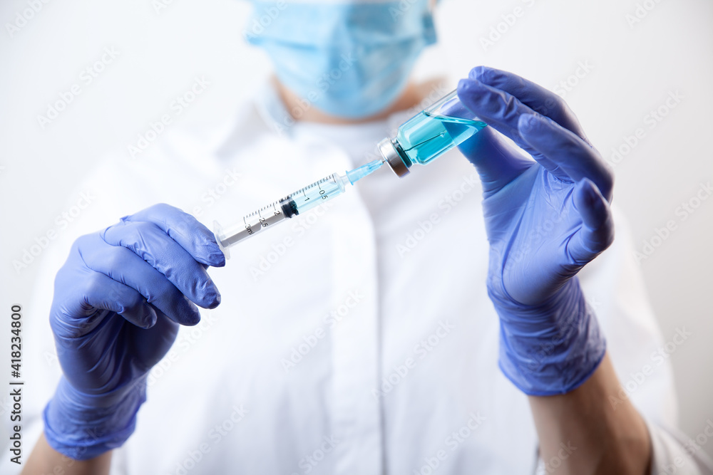 Doctor in gloves filling up syringe from bottle with vaccine, medicine Doctor in gloves filling up syringe from bottle with vaccine, medicine