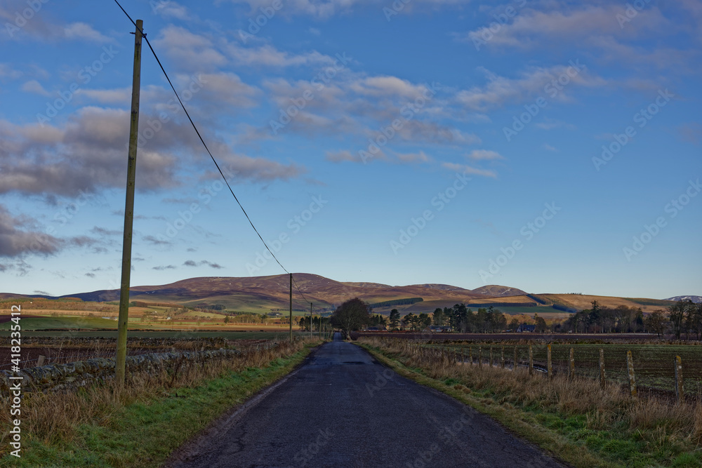 One of the small Minor Scottish Roads leading into the Angus Glens, with the Hill Tops lit up by the morning Light of the Rising sun.