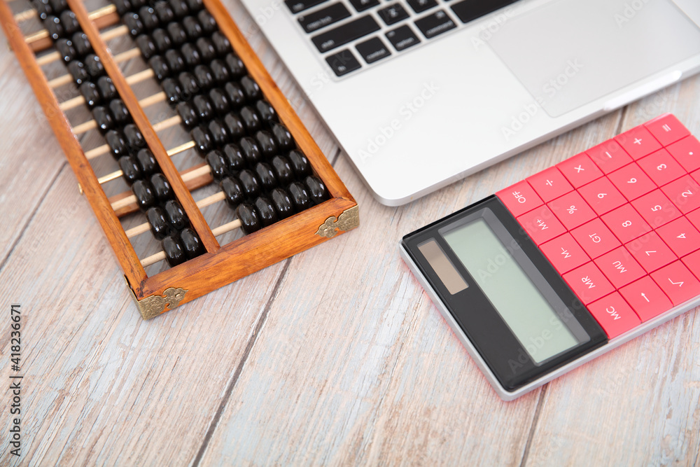 Laptop on the desk, traditional Chinese abacus and red calculator Laptop on the desk, traditional Chinese abacus and red calculator