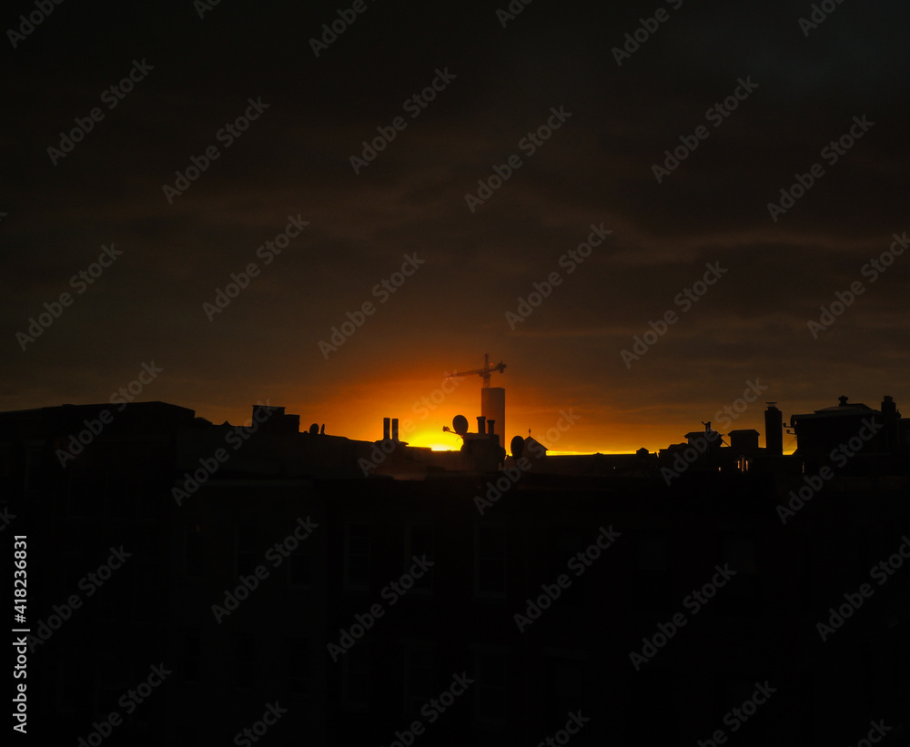 Naklejka premium orange sunset, contrasted with a black silhouette of a construction crane
