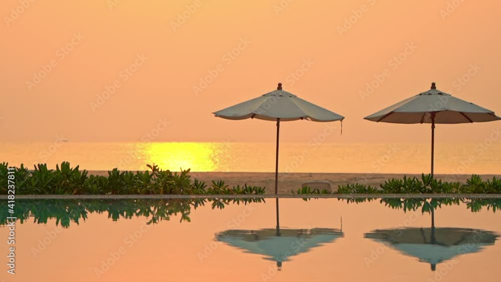 Serene caribbean summer evening scenery, poolside with umbrella reflection and yellow sunlight on sea. Empty pool and tropical beach, full frame Serene caribbean summer evening scenery, poolside with umbrella reflection and yellow sunlight on sea. Empty pool and tropical beach, full frame
