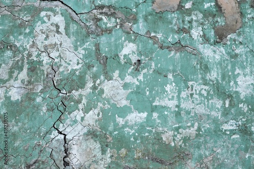 Background texture of a wall with old cracked green plaster.