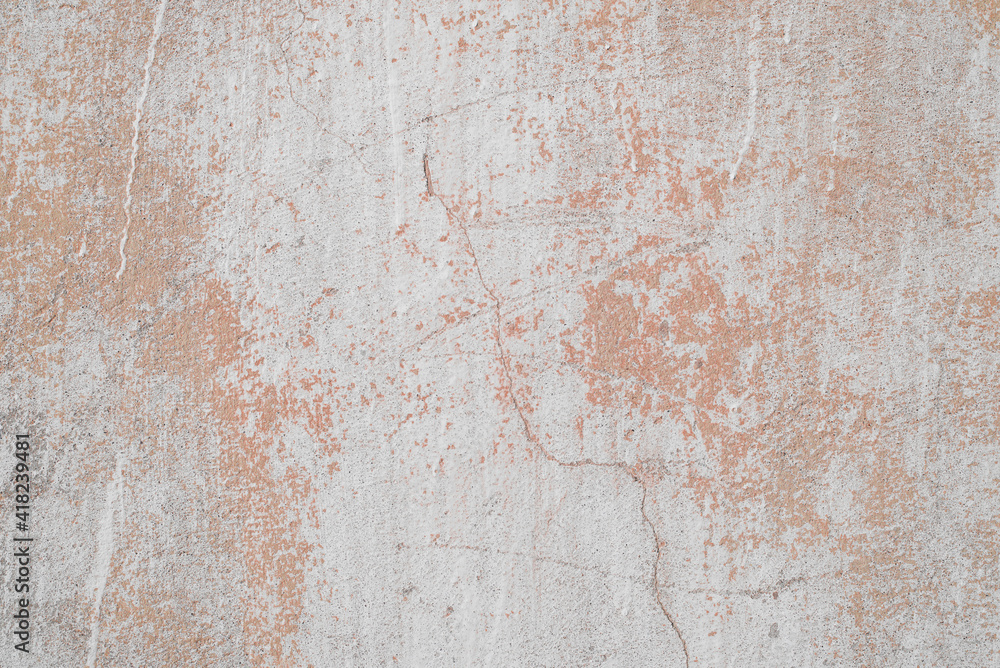Texture of old concrete wall outside, close-up. Faded red paint, scratches, damage.