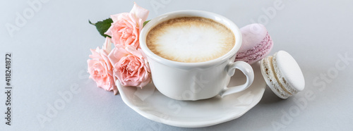 Cup of coffee, pasta for the cake and pink roses on a gray background. Copy space. Banner