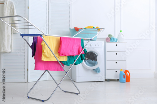 Foto Clean bright laundry hanging on drying rack indoors