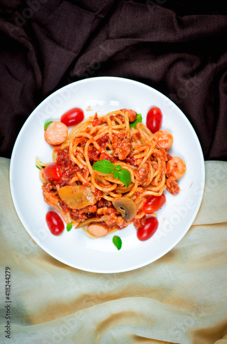 Tasty appetizing classic italian spaghetti pasta with tomato sauce and basil on plate on dark table. View from above, horizontal