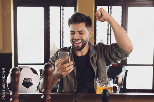 Happy young man after winning of his sports bet in pub