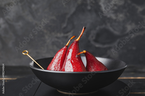 Bowl with sweet poached pears in red wine on dark background