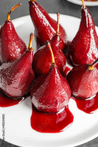 Dessert stand with sweet poached pears in red wine on dark background, closeup