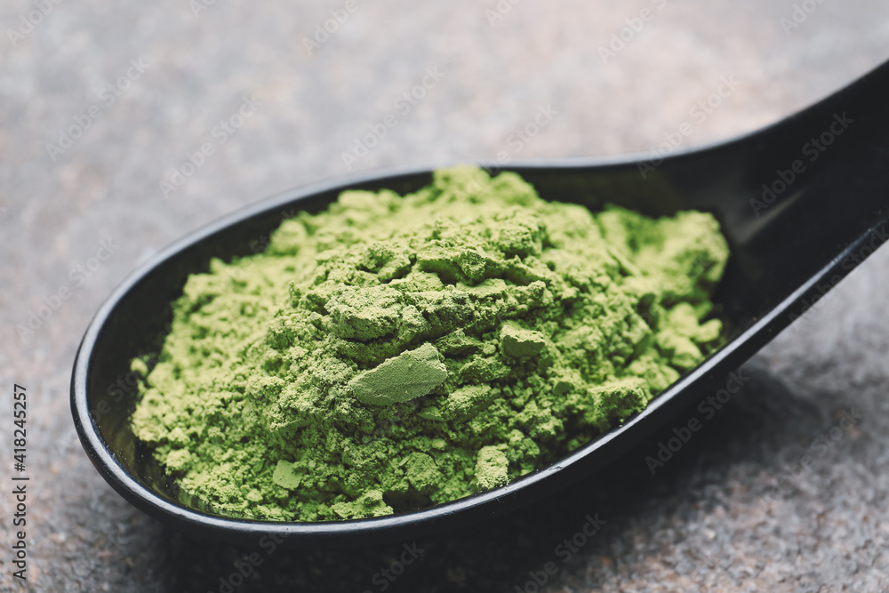 Spoon with powdered matcha tea on grunge background, closeup Spoon with powdered matcha tea on grunge background, closeup