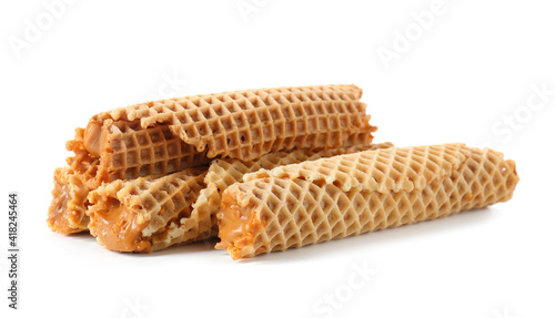Tasty wafer rolls with boiled condensed milk on white background