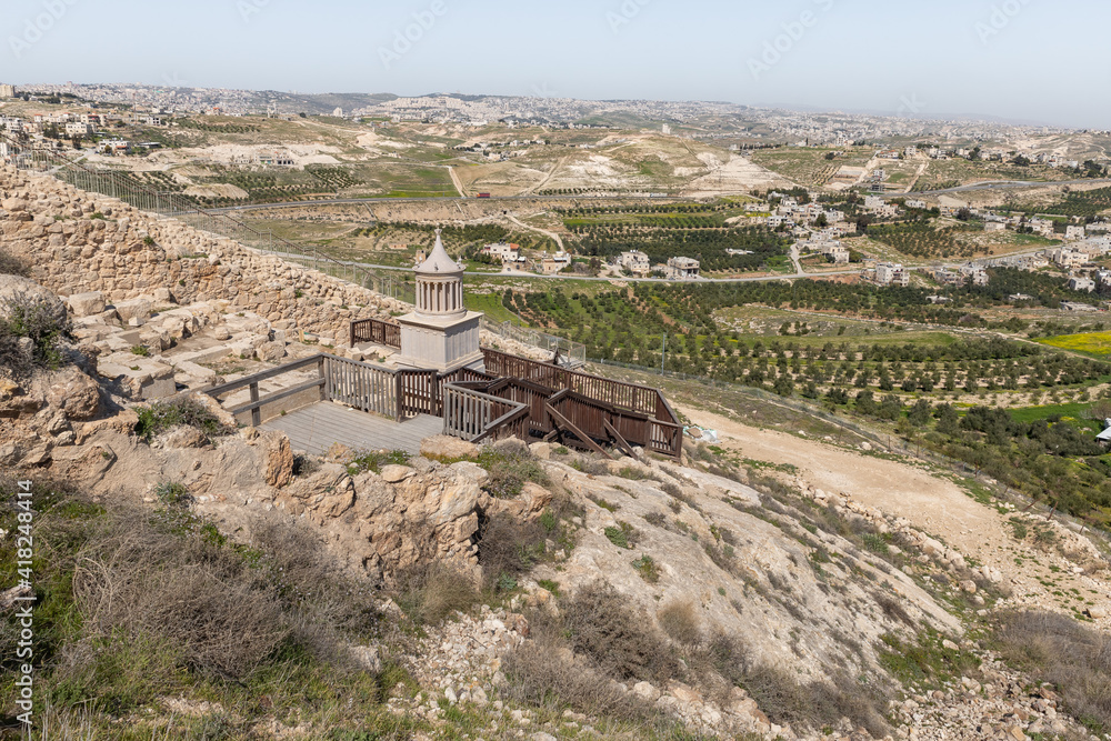 View  from walls of palace ruins of King Herod - Herodion of the restored model of the mausoleum, in which King Herod was buried, and nearby Jewish and Arab settlements in the Judean Desert, in Israel