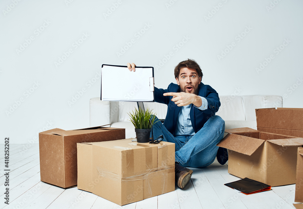 Business man sitting on the floor with boxes unpacking documents to the office manager Business man sitting on the floor with boxes unpacking documents to the office manager