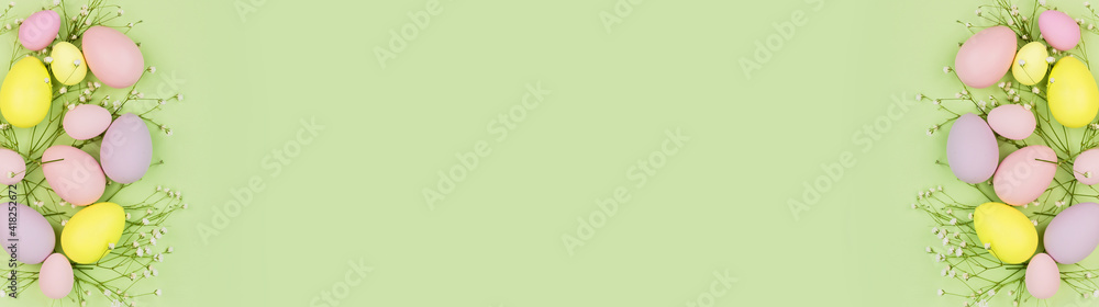 Stylish background with colorful easter eggs pastel colors isolated on green background. Horizontal long banner for web design. Flat lay, top view, mockup, overhead, template