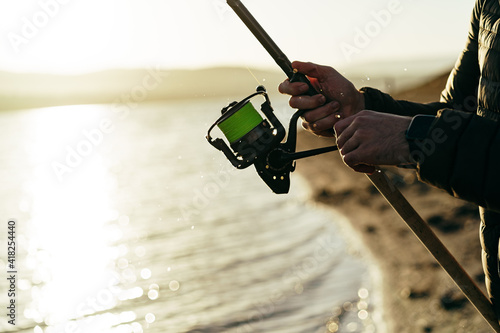 Fisherman hands holding fishing rod close up