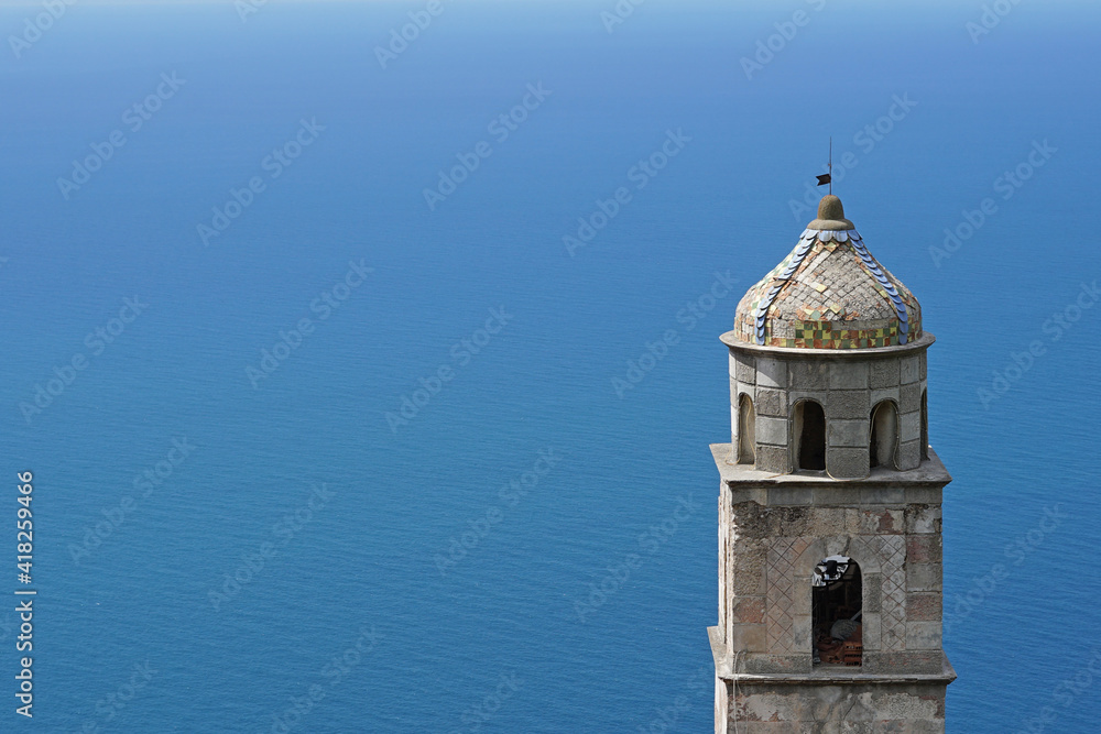 Historic church bell tower above calm sea on Amalfi Coast in Italy, Travel or holiday concept as background
