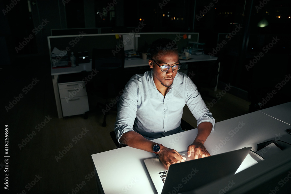 © StratfordProductions - African young business man working at the laptop till late at night in dark office © StratfordProductions - African young business man working at the laptop till late at night in dark office