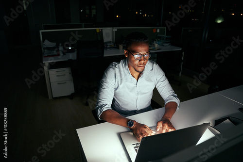 Valokuva African young business man working at the laptop till late at night in dark offi