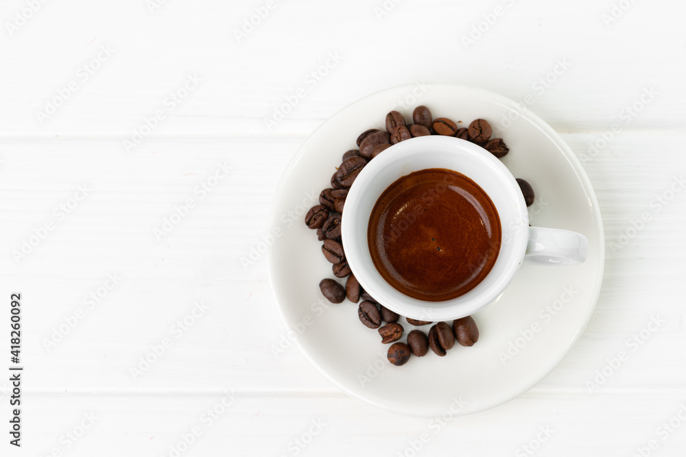 Fototapeta premium Cup of espresso coffee and coffee beans on white surface