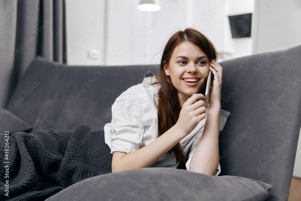 cheerful woman talking on the phone lying on the couch cheerful woman talking on the phone lying on the couch