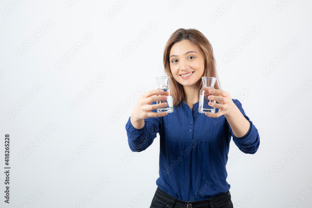 Beautiful woman in blue blouse holding glass of water on white background Beautiful woman in blue blouse holding glass of water on white background