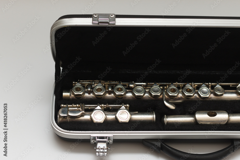 Partial view of a shiny disassembled silver flute in a black case. Studio photo on white background Partial view of a shiny disassembled silver flute in a black case. Studio photo on white background