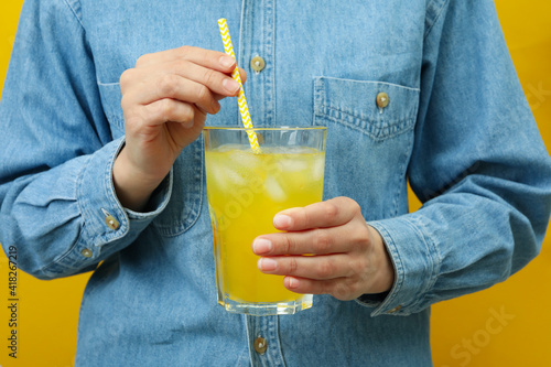 Woman hold glass of soda on yellow background