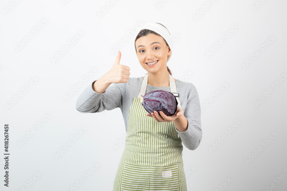 Picture of young woman holding purple cabbage and giving thumbs up