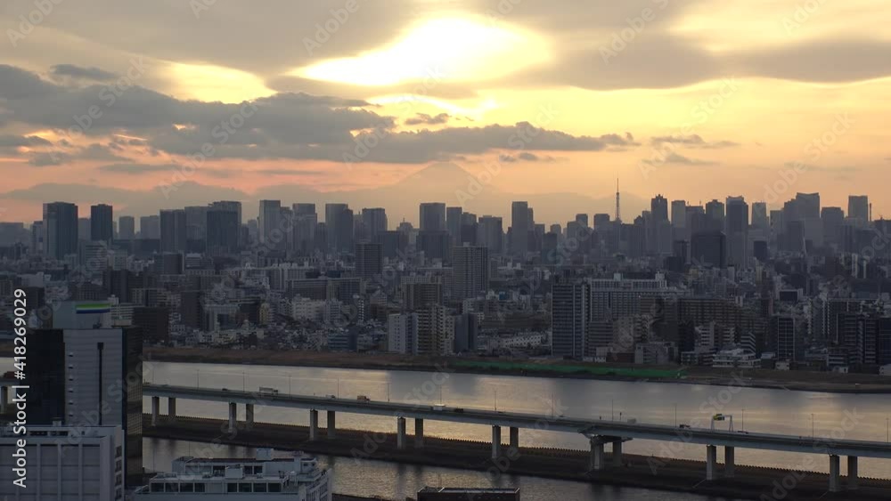 TOKYO, JAPAN : Aerial sunset CITYSCAPE of TOKYO and MOUNT FUJI. View of sun, river and buildings at downtown area. Japanese urban metropolis and nature concept. Time lapse zoom in shot dusk to night.