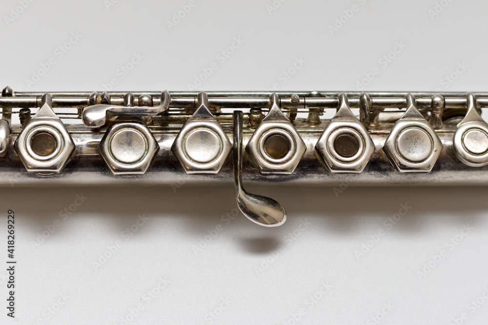 Obraz premium Silver flute with keys on a white sheet