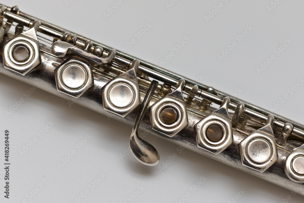 Fototapeta premium A shiny silver flute lies diagonally on a white sheet