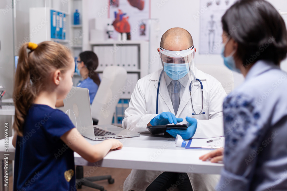 Pediatrician doctor writing notes on notepad during medical checkup examination. Physician specialist in pediatry medicine providing professional treatment services in protective equipment Pediatrician doctor writing notes on notepad during medical checkup examination. Physician specialist in pediatry medicine providing professional treatment services in protective equipment
