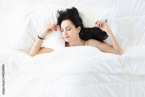 Young brunette woman sleeping in white bed top view