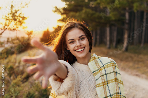 Obraz na plátně happy woman stretches her hand forward on nature near green bushes