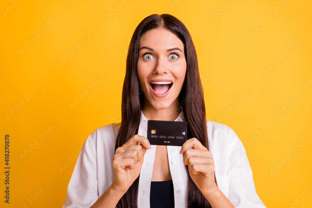 Portrait of pretty astonished lady arms hold banking debit card open mouth isolated on yellow color background Portrait of pretty astonished lady arms hold banking debit card open mouth isolated on yellow color background