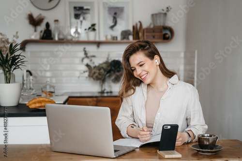 Joyful blonde girl smiling and talking via video call on laptop, home office, working remotely, explaining a strategy, freelancer, discussing a new project with team